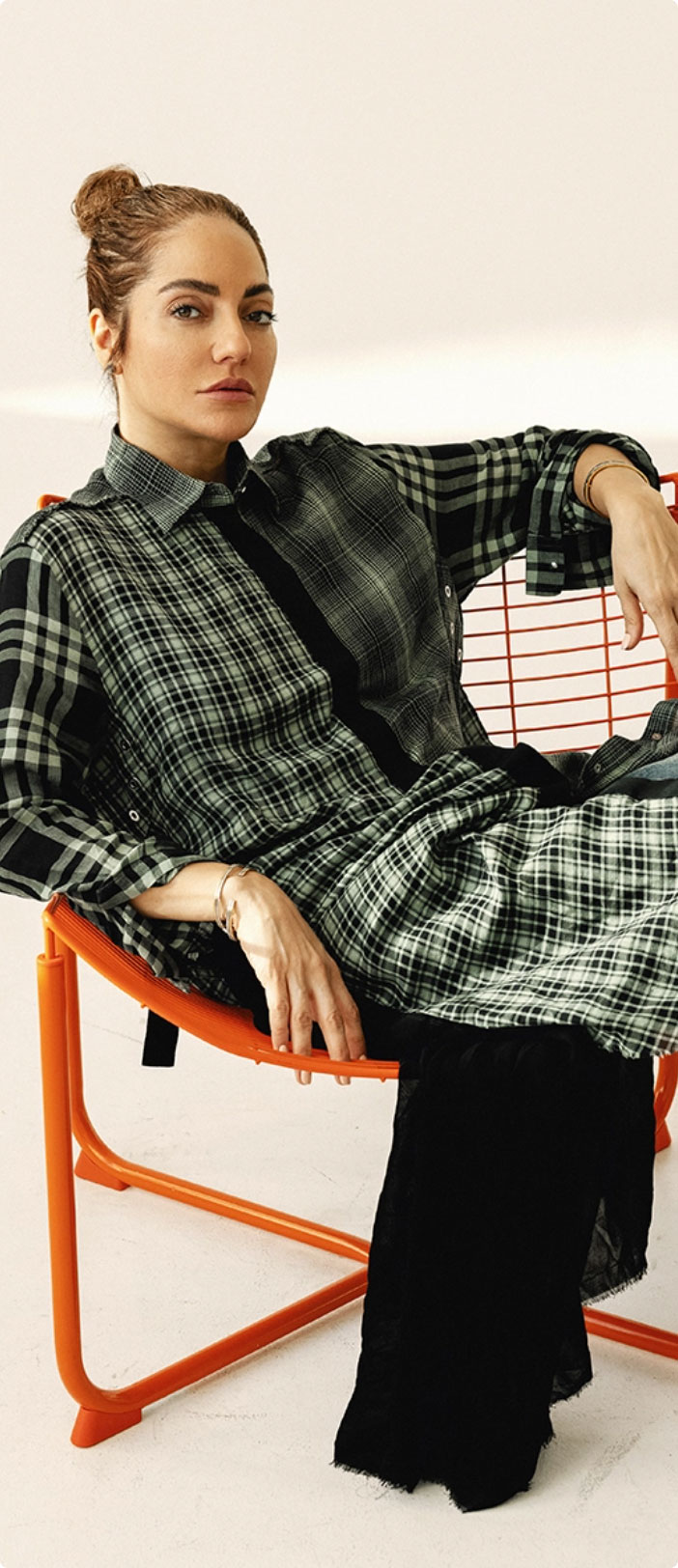 Woman in a plaid dress seated on an orange chair