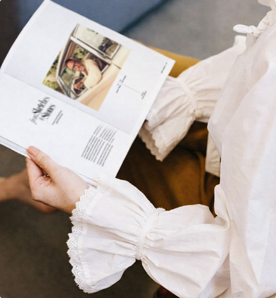 Woman in a white blouse reading ALEPH Magazine